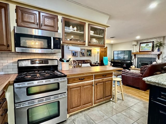 kitchen featuring stainless steel appliances, backsplash, and wood counters