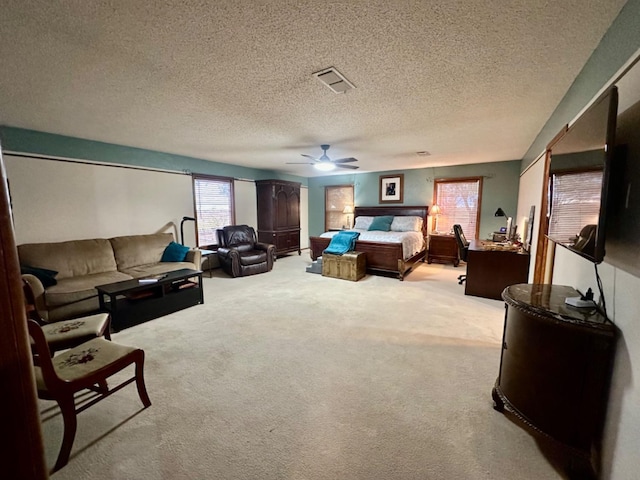 bedroom with ceiling fan, light carpet, and a textured ceiling