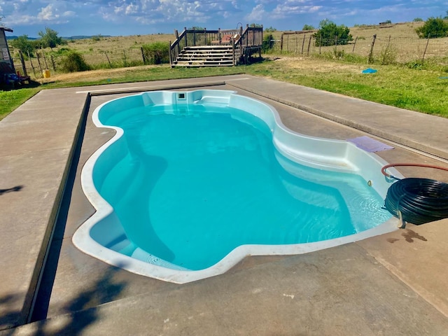 view of swimming pool featuring a yard and a deck