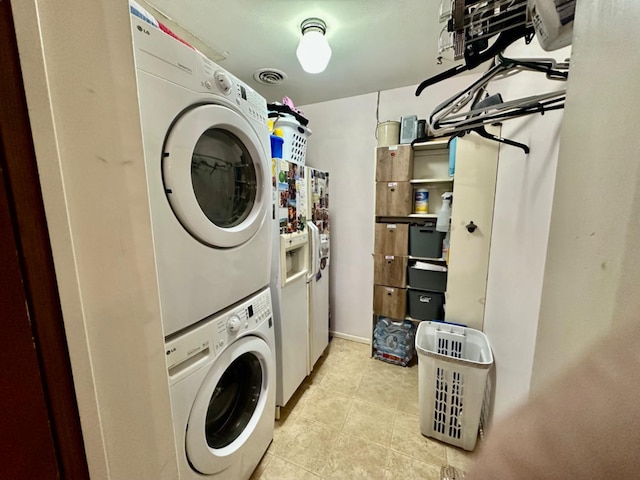 laundry room with stacked washer / dryer and light tile patterned floors