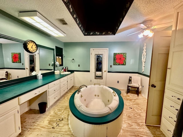 bathroom with vanity, ceiling fan, a textured ceiling, and a bathtub