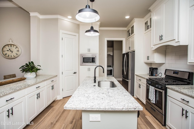 1308 Dover Ln, Wolfforth, TX 79382 - kitchen featuring appliances with stainless steel finishes, a sink, a center island with sink, tasteful backsplash, and white cabinetry