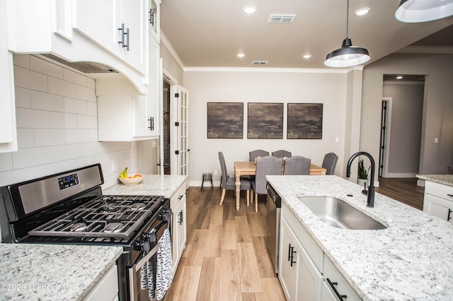 1308 Dover Ln, Wolfforth, TX 79382 - kitchen featuring appliances with stainless steel finishes, a sink, light wood finished floors, ornamental molding, and white cabinetry