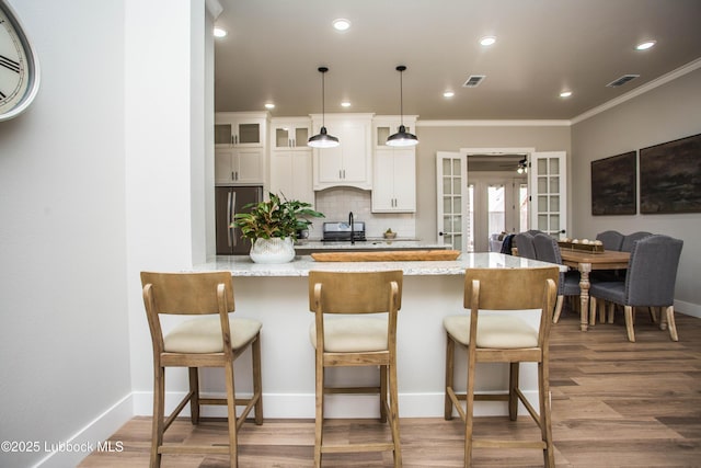 1308 Dover Ln, Wolfforth, TX 79382 - kitchen with freestanding refrigerator, french doors, a kitchen breakfast bar, white cabinets, and ornamental molding