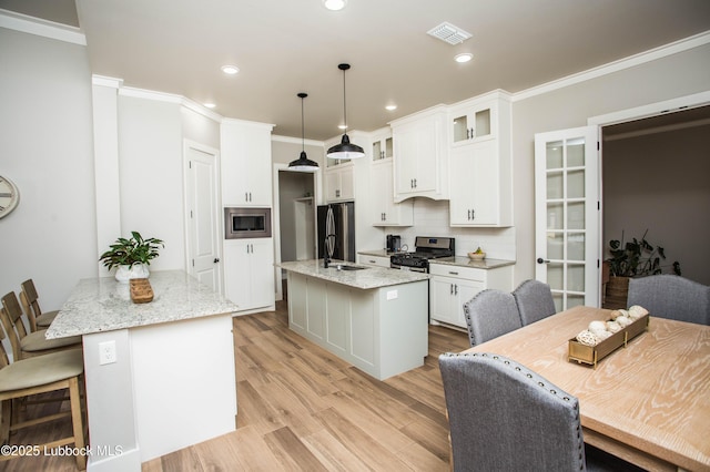 1308 Dover Ln, Wolfforth, TX 79382 - kitchen with stainless steel appliances, a kitchen island with sink, white cabinets, glass insert cabinets, and decorative backsplash