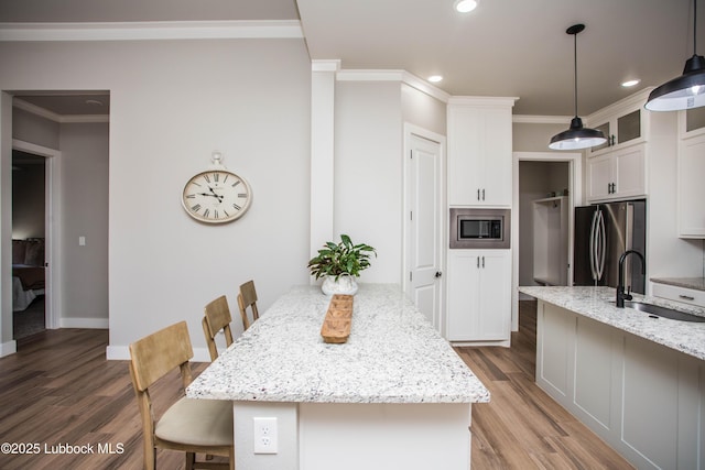 1308 Dover Ln, Wolfforth, TX 79382 - kitchen featuring a sink, appliances with stainless steel finishes, ornamental molding, a breakfast bar area, and light wood-style flooring