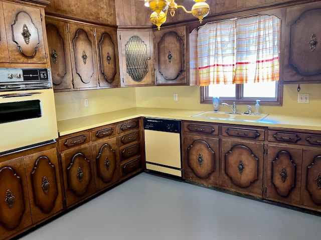 kitchen with sink, dishwasher, dark brown cabinets, oven, and a chandelier