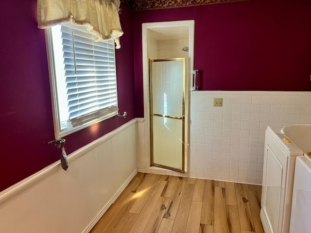 bathroom featuring washer and clothes dryer, shower with separate bathtub, and wood-type flooring