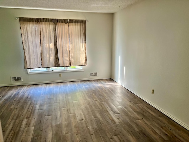 empty room featuring hardwood / wood-style flooring and a textured ceiling