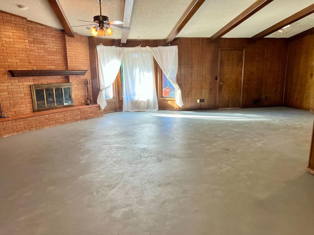 unfurnished living room with a textured ceiling, concrete floors, a fireplace, and wood walls