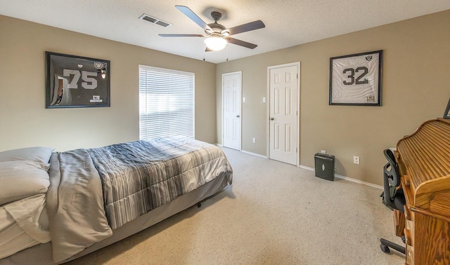 carpeted bedroom featuring ceiling fan and a textured ceiling