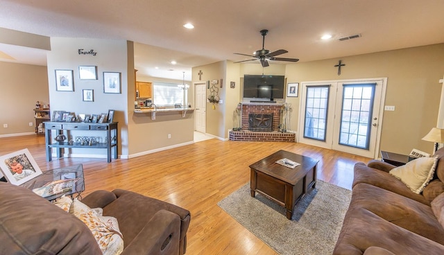 living room featuring ceiling fan, a fireplace, light hardwood / wood-style floors, and a healthy amount of sunlight