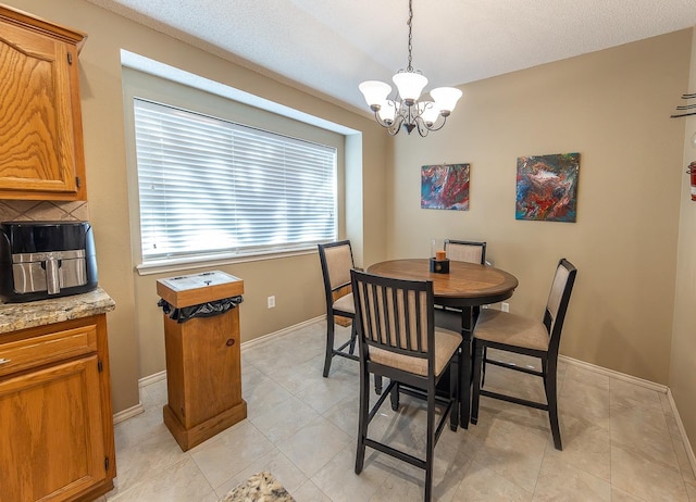 dining area with a notable chandelier, light tile patterned floors, and a textured ceiling