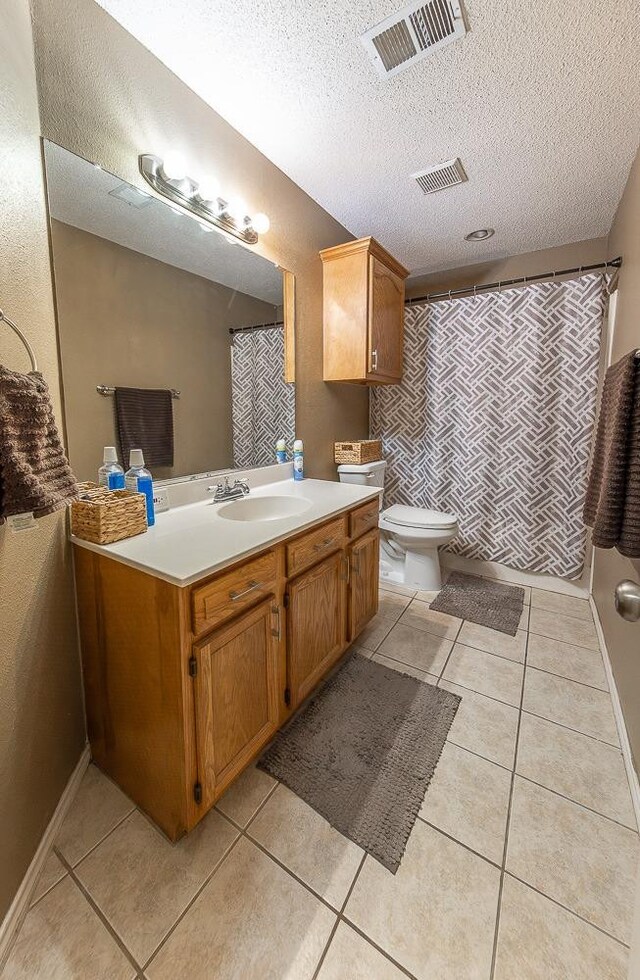 bathroom featuring vanity, tile patterned floors, toilet, and a textured ceiling