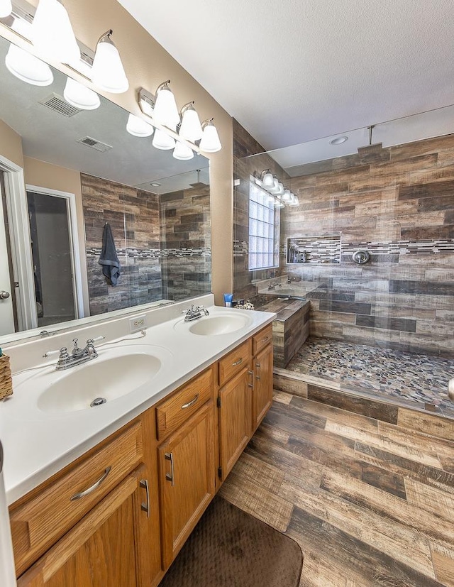 bathroom featuring tiled shower, vanity, and a textured ceiling