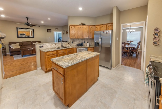 kitchen featuring sink, appliances with stainless steel finishes, kitchen peninsula, a kitchen island, and backsplash