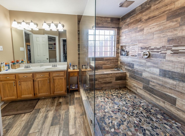 bathroom with hardwood / wood-style flooring, vanity, and a tile shower