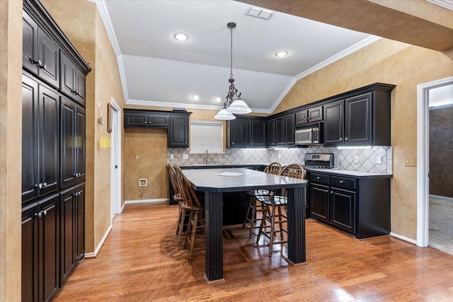 kitchen featuring lofted ceiling, hardwood / wood-style flooring, ornamental molding, and a breakfast bar