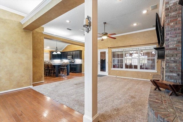 interior space with crown molding, wood-type flooring, a textured ceiling, and ceiling fan