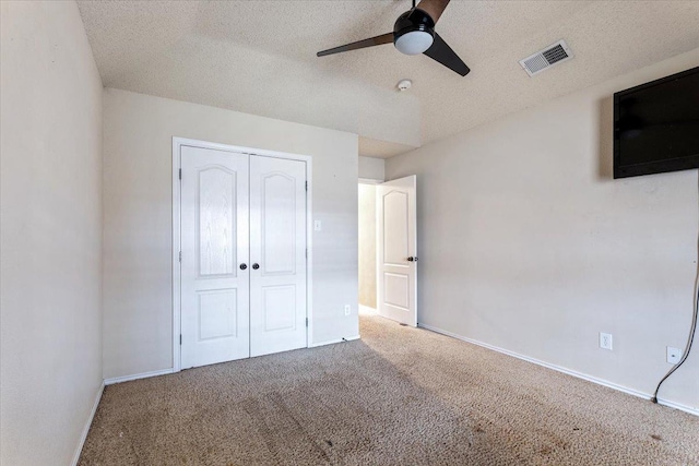 unfurnished bedroom featuring ceiling fan, a closet, a textured ceiling, and carpet