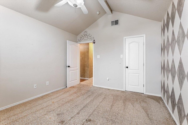 unfurnished bedroom with carpet, vaulted ceiling with beams, a textured ceiling, and ceiling fan