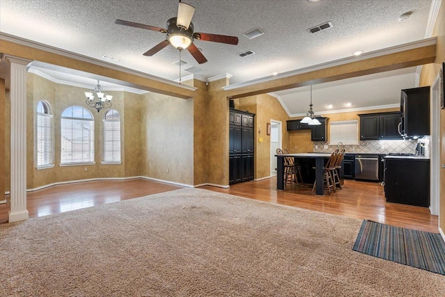 unfurnished living room with decorative columns, ornamental molding, a textured ceiling, ceiling fan with notable chandelier, and light colored carpet