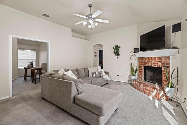 living room featuring a fireplace, light colored carpet, and ceiling fan