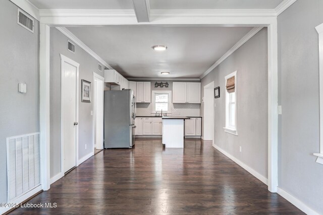 5320 25th St, Lubbock, TX 79407 - kitchen with freestanding refrigerator, dark wood finished floors, white cabinets, backsplash, and crown molding