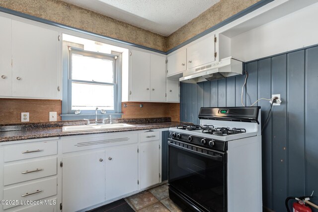 5320 25th St, Lubbock, TX 79407 - kitchen featuring gas range, under cabinet range hood, a sink, white cabinets, and dark countertops