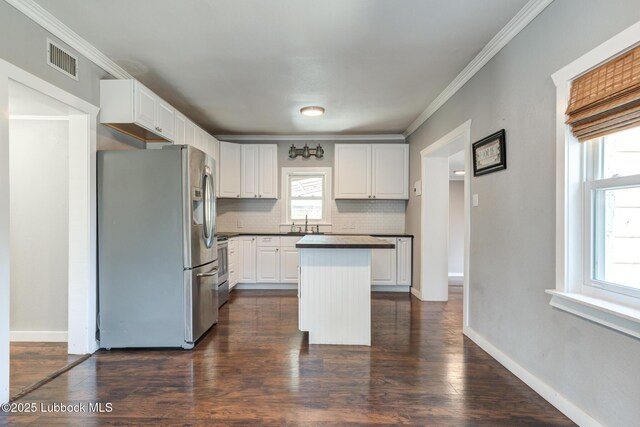 5320 25th St, Lubbock, TX 79407 - kitchen featuring appliances with stainless steel finishes, dark countertops, white cabinetry, backsplash, and a kitchen island