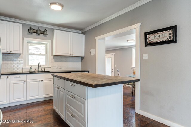 5320 25th St, Lubbock, TX 79407 - kitchen featuring butcher block counters, a sink, decorative backsplash, ornamental molding, and dark wood-style flooring