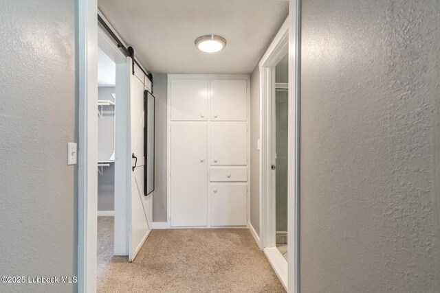 5320 25th St, Lubbock, TX 79407 - hall featuring light carpet, a textured wall, a barn door, and baseboards