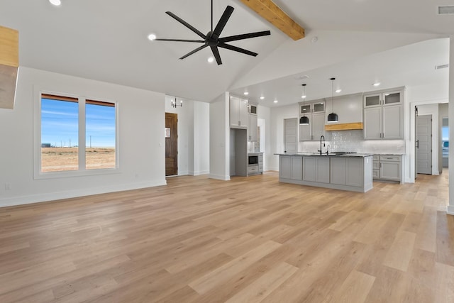 unfurnished living room featuring high vaulted ceiling, sink, beam ceiling, ceiling fan, and light wood-type flooring