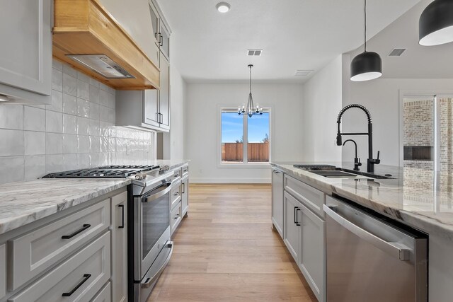 kitchen with hanging light fixtures, premium range hood, appliances with stainless steel finishes, and sink