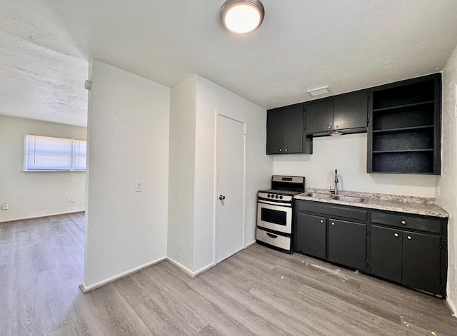 kitchen featuring sink, gas stove, a textured ceiling, and light wood-type flooring