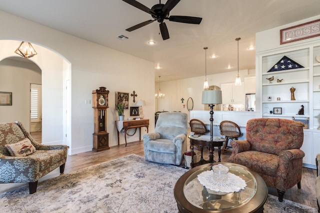 living room featuring ceiling fan with notable chandelier and hardwood / wood-style floors