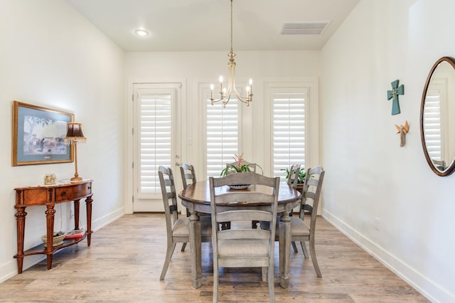 dining area with light wood-type flooring and a notable chandelier