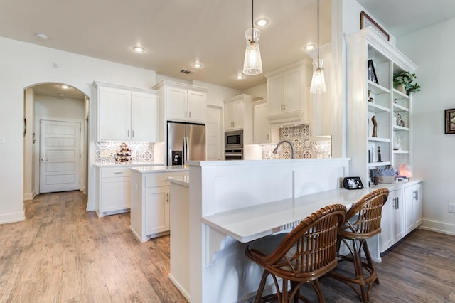 kitchen featuring white cabinetry, stainless steel appliances, kitchen peninsula, and hanging light fixtures