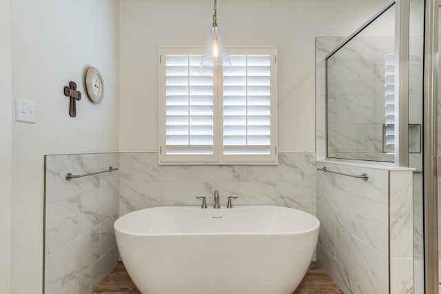 bathroom with shower with separate bathtub and tile walls