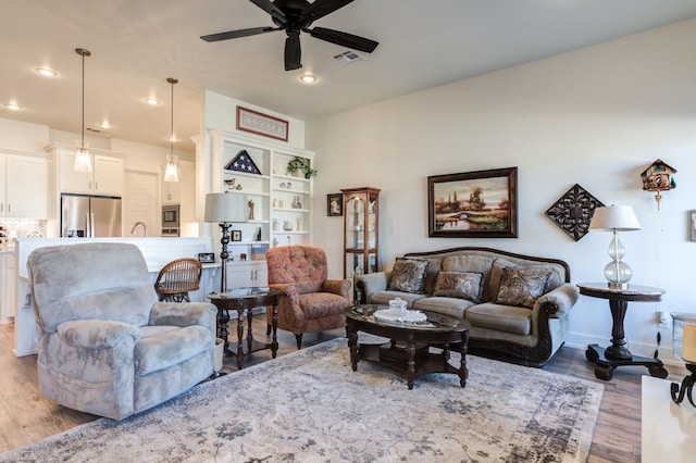 living room with ceiling fan and light hardwood / wood-style flooring