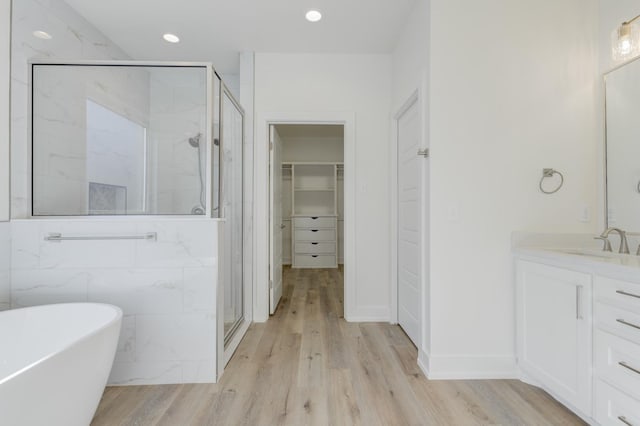 bathroom with independent shower and bath, vanity, and hardwood / wood-style floors