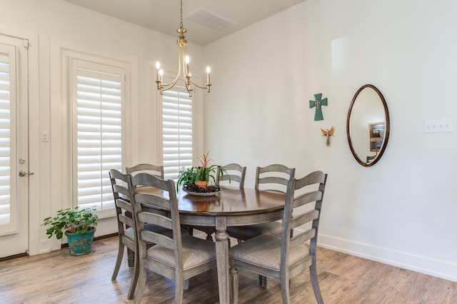 dining space featuring wood-type flooring and an inviting chandelier