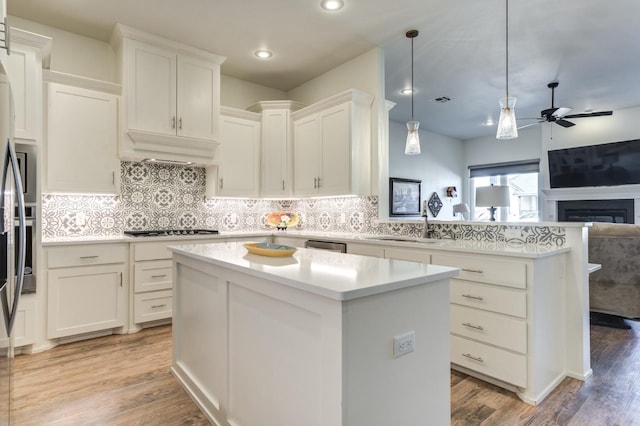 kitchen with premium range hood, gas stovetop, a center island, hanging light fixtures, and white cabinets