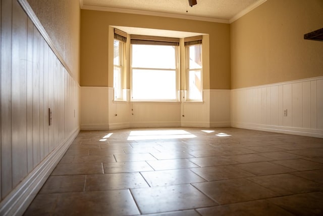 empty room with ceiling fan, ornamental molding, and a textured ceiling