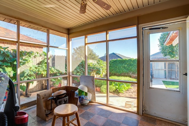 sunroom featuring a healthy amount of sunlight, wood ceiling, and ceiling fan