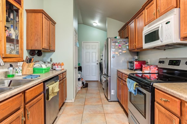 kitchen with light tile patterned floors, vaulted ceiling, and appliances with stainless steel finishes