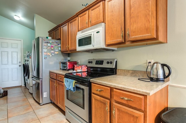 kitchen with light tile patterned flooring, washing machine and clothes dryer, and stainless steel appliances