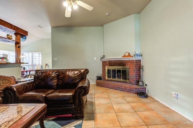 living room featuring ceiling fan, a fireplace, vaulted ceiling, and light tile patterned flooring