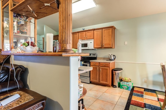 kitchen with stainless steel range with electric stovetop and light tile patterned flooring