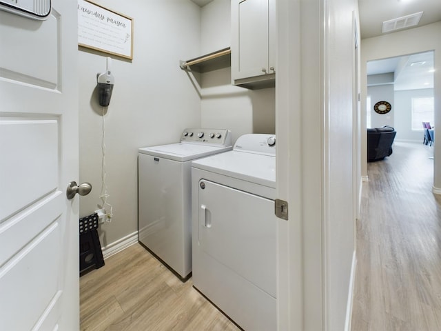 washroom with light hardwood / wood-style flooring, washer and clothes dryer, and cabinets